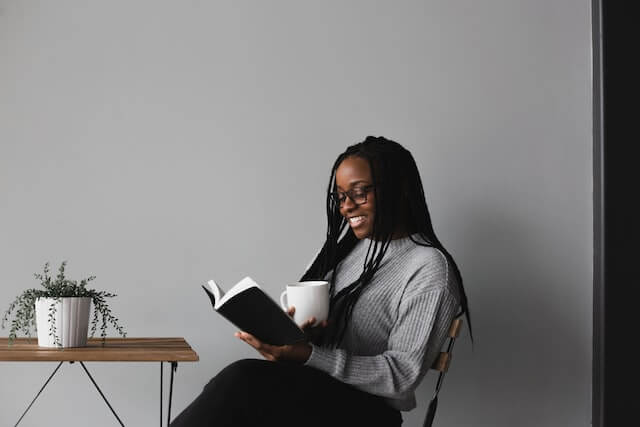Woman sitting at a small desk reading a book.