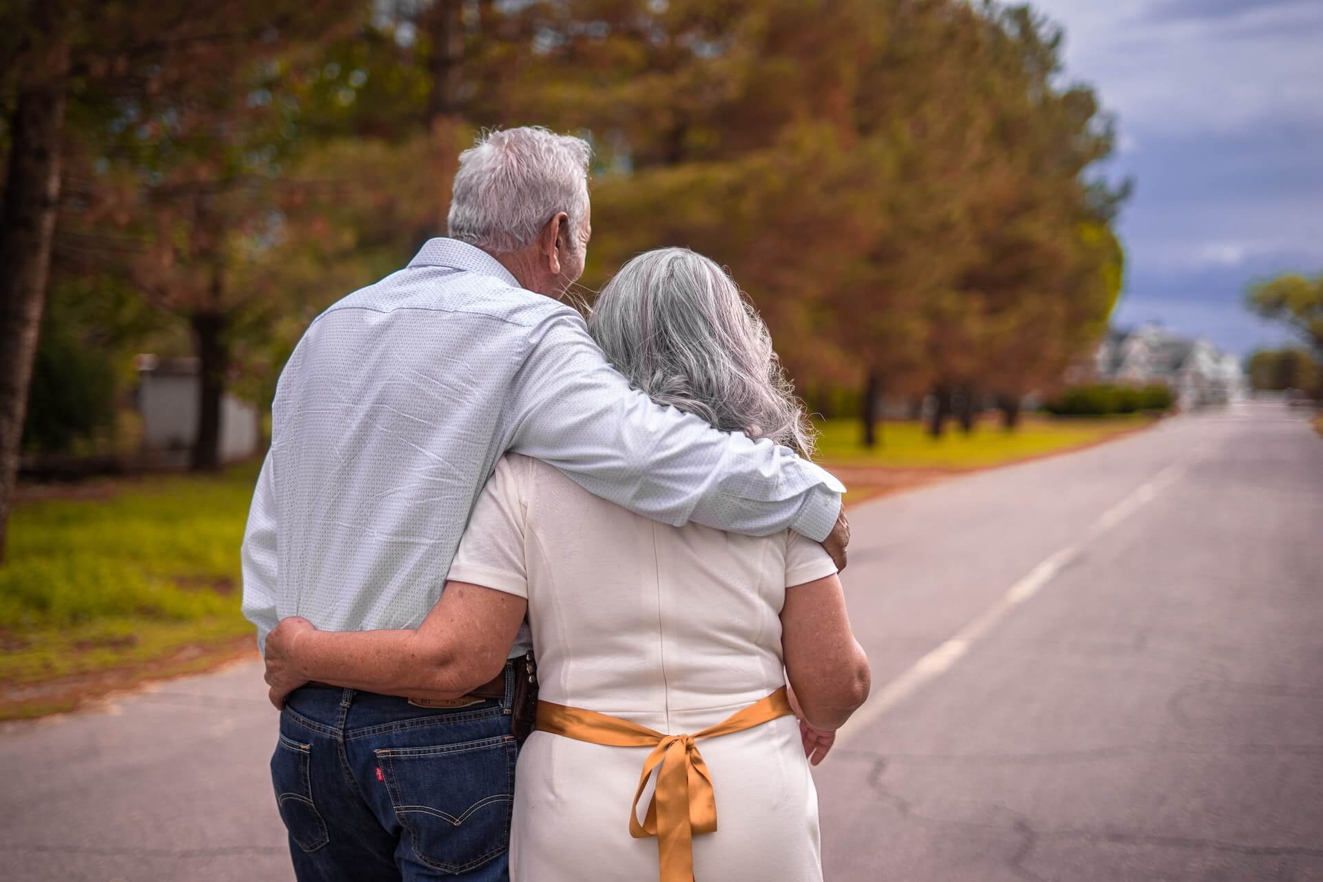 Senior couple walking hugged down the road