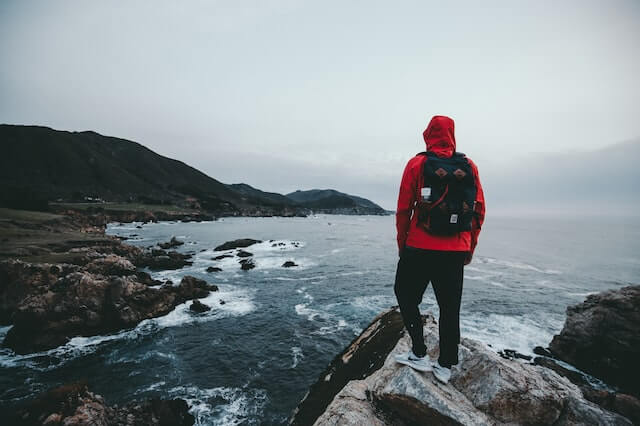 Man with a back pack standing on a shore.